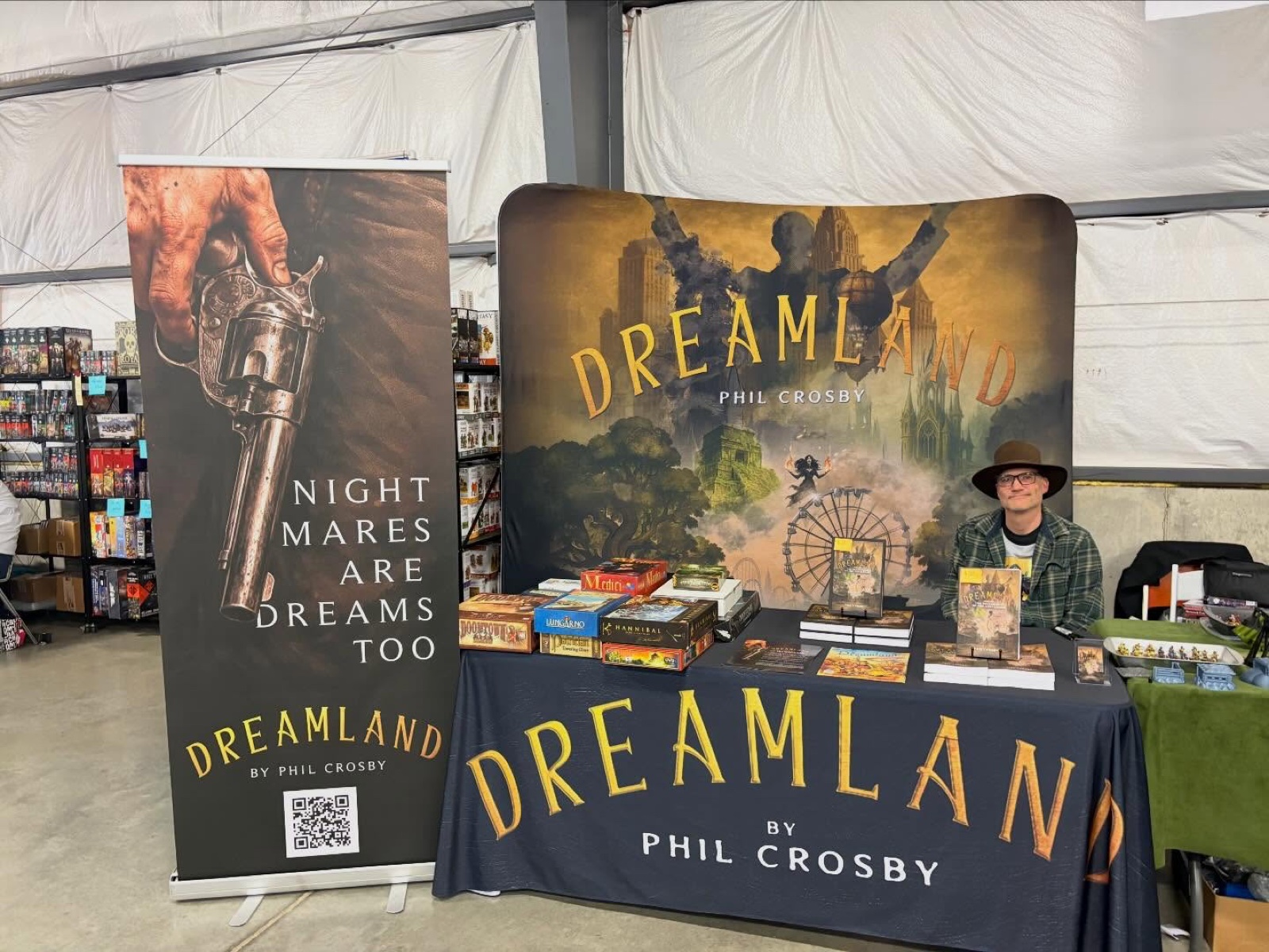 The DreamLand convention booth with the full park artwork on a backdrop banner and a second banner reading Nightmares Are Dreams Too