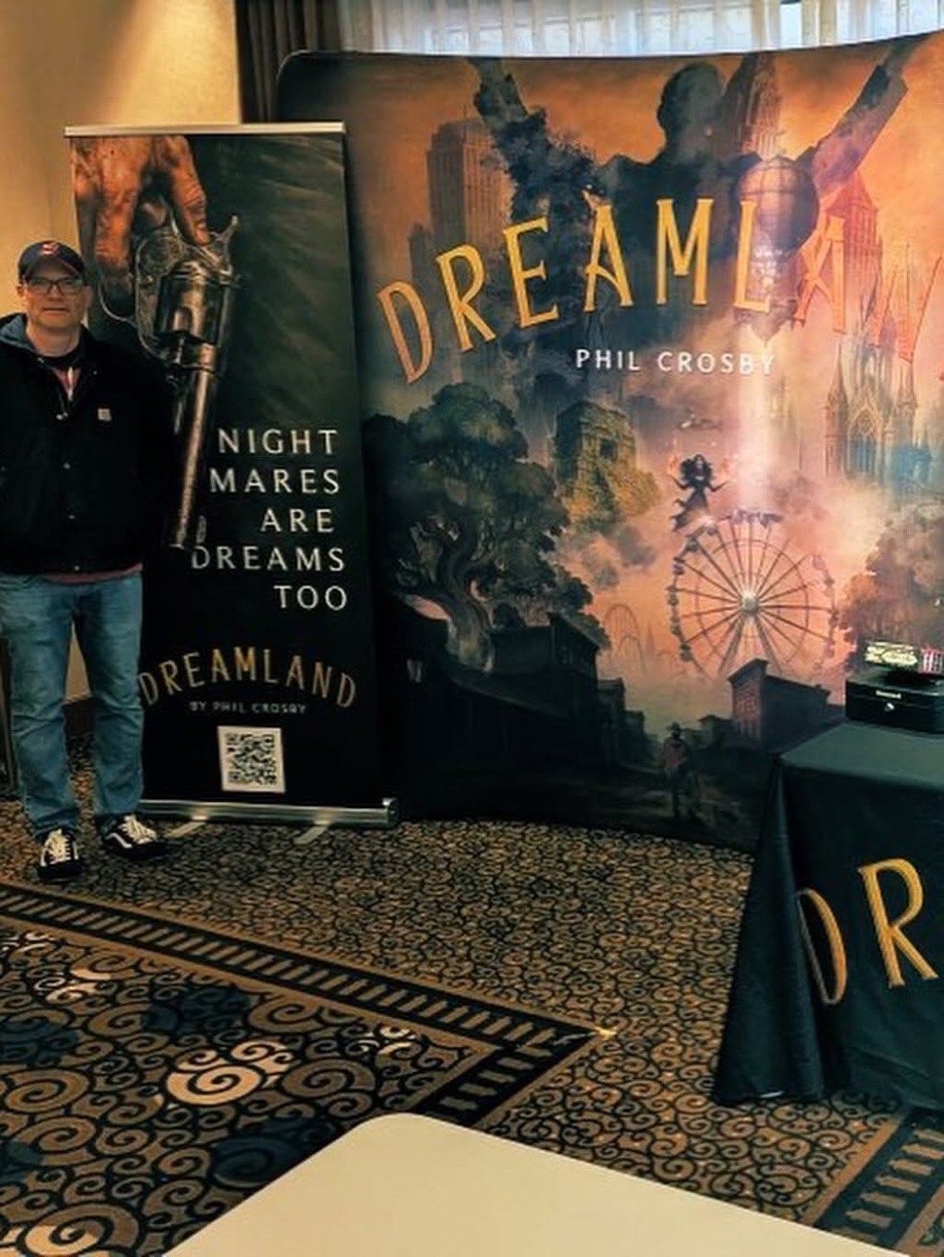 Phil Crosby beside the Nightmares Are Dreams Too banner and the DreamLand backdrop at a convention